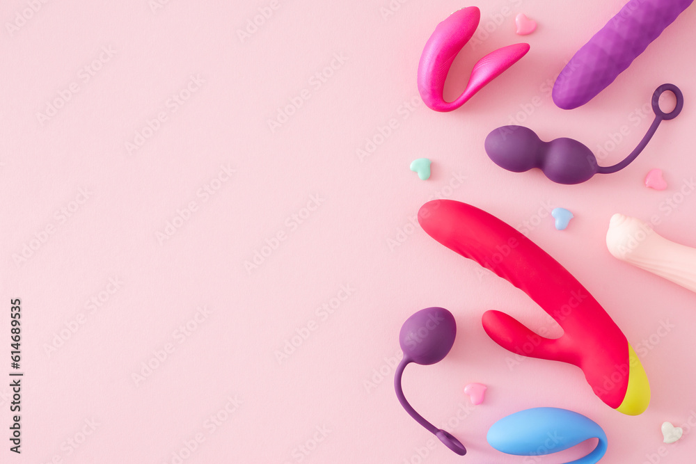 Concept of adult toys for erotic indulgence. Top view arrangement of vibrator, vaginal balls, massager for the clitoris and colorful hearts on pastel pink background with empty space for text or ad Concept of adult toys for erotic indulgence. Top view arrangement of vibrator, vaginal balls, massager for the clitoris and colorful hearts on pastel pink background with empty space for text or ad