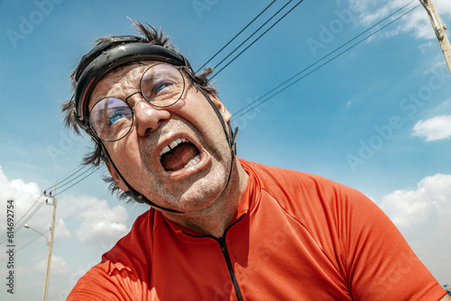 An exhausted cyclist is riding a bicycle under a blue sky