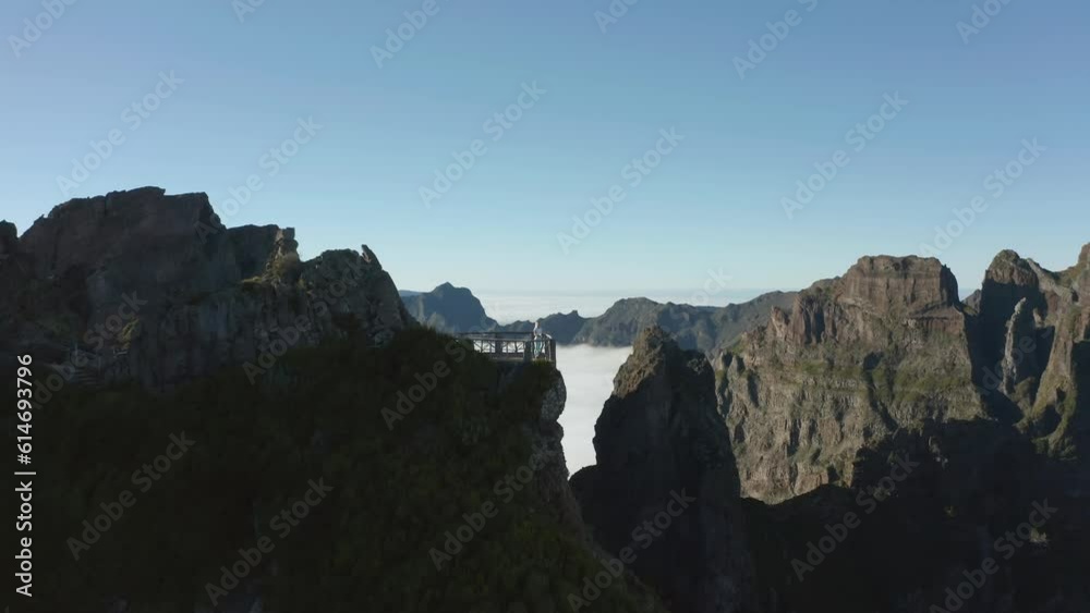 Woman standing on rock viewpoint high in Madeira mountains, aerial Woman standing on rock viewpoint high in Madeira mountains, aerial