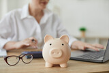 Piggy bank in form of pig on background of financial advisor who plans annual budget. Close up of piggy bank on table. Business, finance, investment, saving and corruption concept.