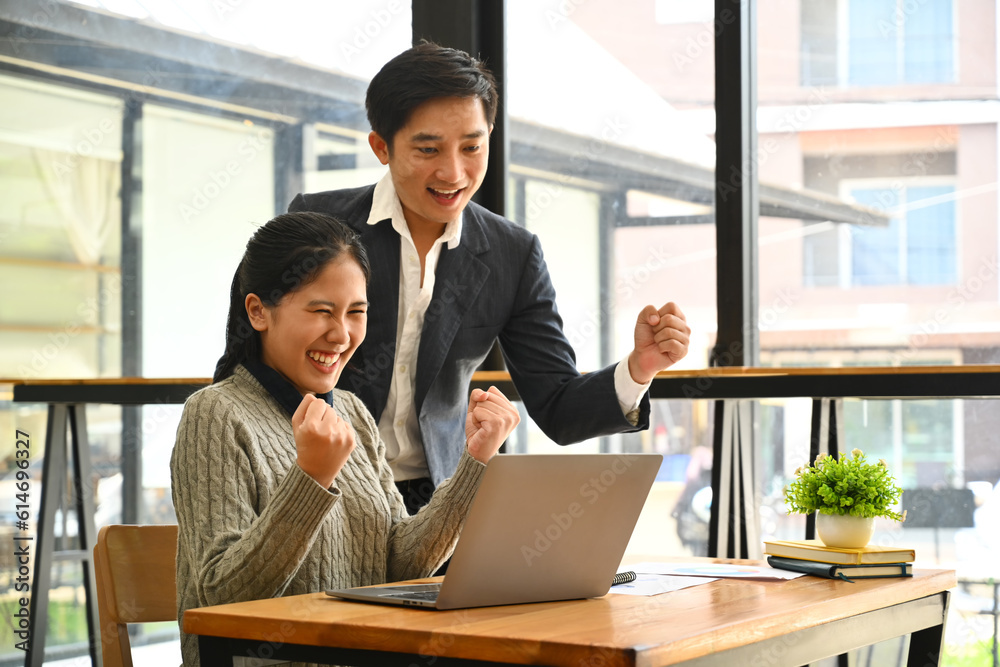 Happy businesspeople looking at laptop screen excited by good news online, celebrating success raising hands up Happy businesspeople looking at laptop screen excited by good news online, celebrating success raising hands up