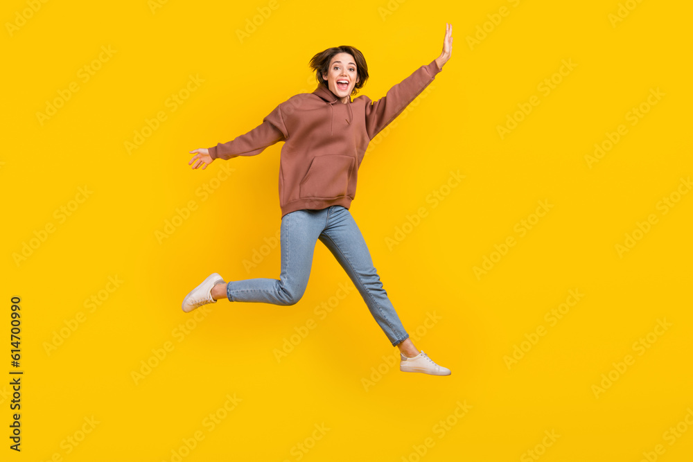 Full body photo of young model woman jump flying hands wear trendy sweatshirt have fun careless weekend isolated on yellow color background