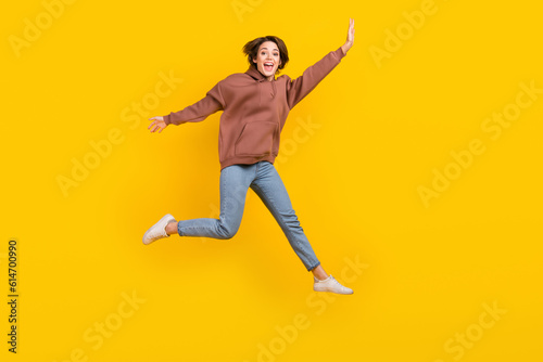 Full body photo of young model woman jump flying hands wear trendy sweatshirt have fun careless weekend isolated on yellow color background