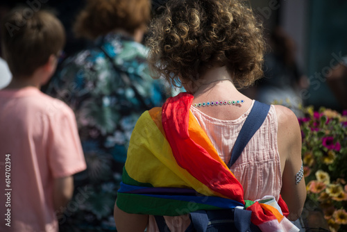 Portrait on back view of woman walking in the street with rainbow flags