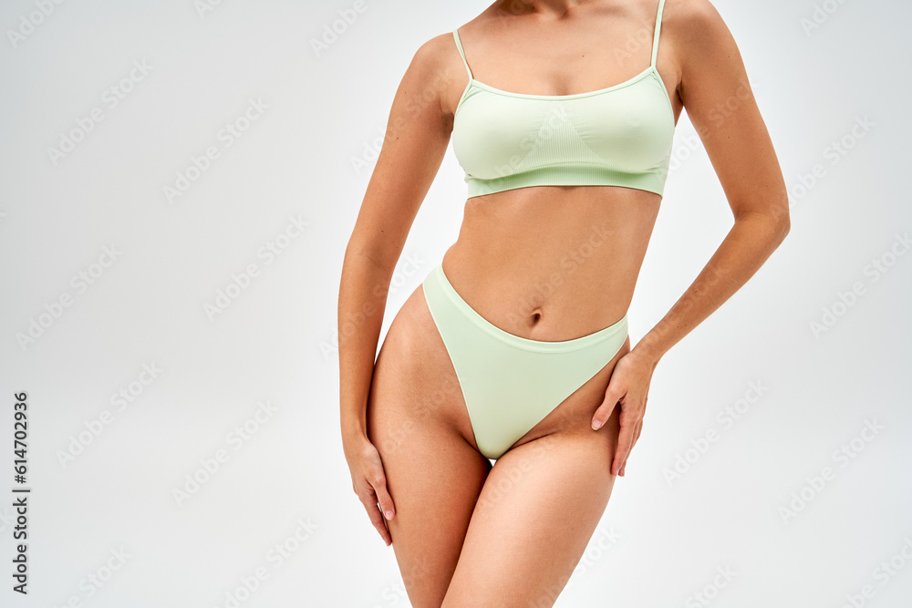Cropped view of seductive young woman in modern light green panties and bra touching hip and standing isolated on grey, self-acceptance and body positive concept, femininity, body love Cropped view of seductive young woman in modern light green panties and bra touching hip and standing isolated on grey, self-acceptance and body positive concept, femininity, body love
