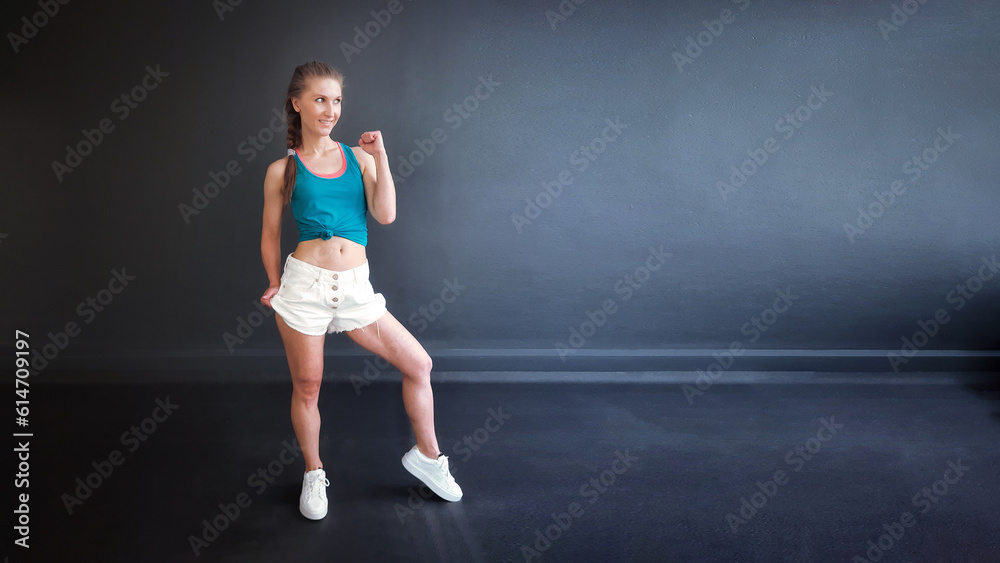 Fitness trainer shows exercises with green dumbbells in his hands. Chest and arm workout. Workout in the gym on the background of a black wall. Biceps and triceps workout with dumbbells.