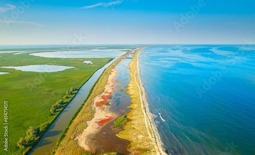 Black Sea shore in Danube Delta. Aerial view over this amazing Gura Portitei resort in Romania during a beautiful sunny day. Blue sea water landscape and red algae.