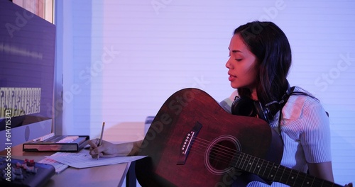 Fotografi Happy young asian woman songwriter play acoustic guitar think and write notes lyrics song in paper