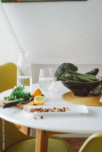 Healthy food concept. Fruits, nuts and vegetables in the kitchen. Nuts, lemon, salad, asparagus and broccoli are waiting for the cooking on white table. Preparing healthy dinner. Vegetarian meal