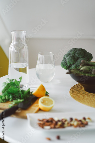 Healthy food concept. Fruits  nuts and vegetables in the kitchen. Nuts  lemon  salad  asparagus and broccoli are waiting for the cooking on white table. Preparing healthy dinner. Vegetarian meal