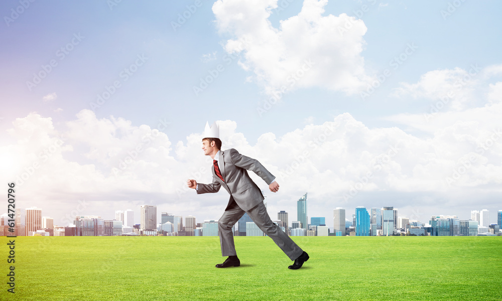 King businessman in elegant suit running on green grass and modern cityscape at background