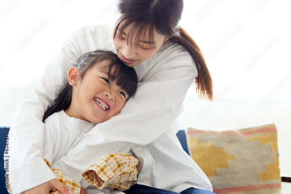 ソファーの上で元気よく遊ぶ幸せそうな日本人の母親と子供