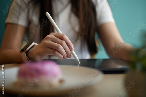 Graphic designer drawing a sketch with a stylus pen on a tablet computer in a cafe. Freelance illustrator working on a modern portable gadget