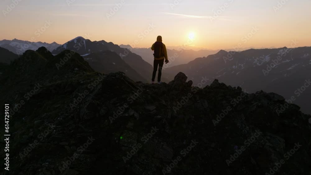 Male mountaineer standing on a mountain looking at the sunrise in the Alps. Male mountaineer standing on a mountain looking at the sunrise in the Alps.