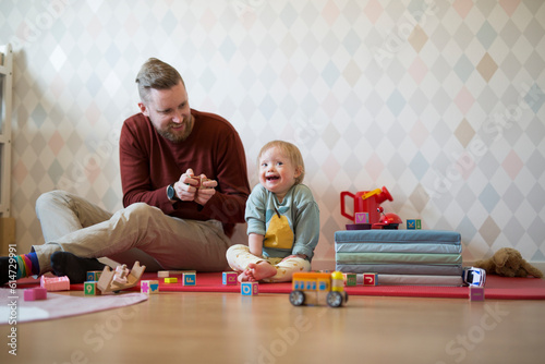 Father playing with baby with down syndrome photo