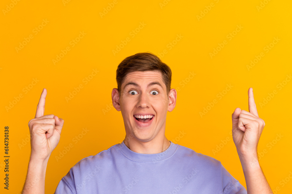 Cheerful handsome man showing direction and pointing with finger up empty space on yellow color background Cheerful handsome man showing direction and pointing with finger up empty space on yellow color background