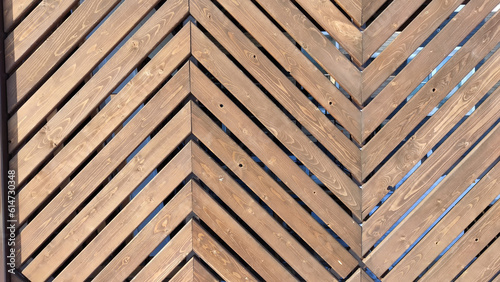 Fence made of wooden slats with a pattern in the shape of a fir tree as a Location  Background  texture  copy of space  frame. Abstract natural graphic resource