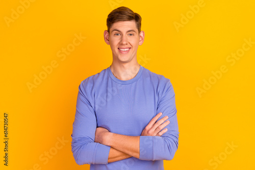 Portrait of attractive wearing casual classic sweater macho man standing with folded arms isolated on yellow background