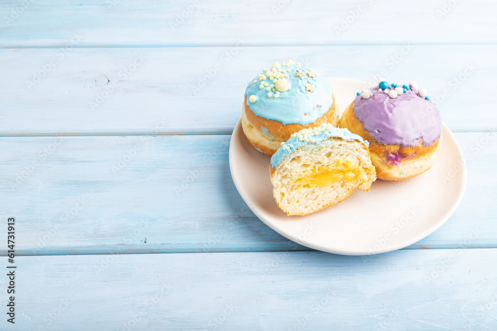 Purple and blue glazed donut on blue wooden, side view, copy space. Purple and blue glazed donut on blue wooden, side view, copy space.