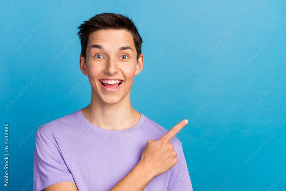 Handsome smiling man pointing away empty space incredible ads isolated on blue background Handsome smiling man pointing away empty space incredible ads isolated on blue background
