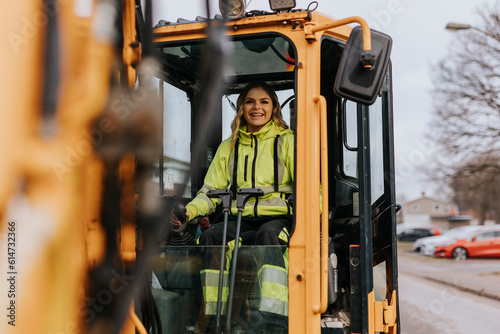 Portrait of smiling female road worker operating excavator photo