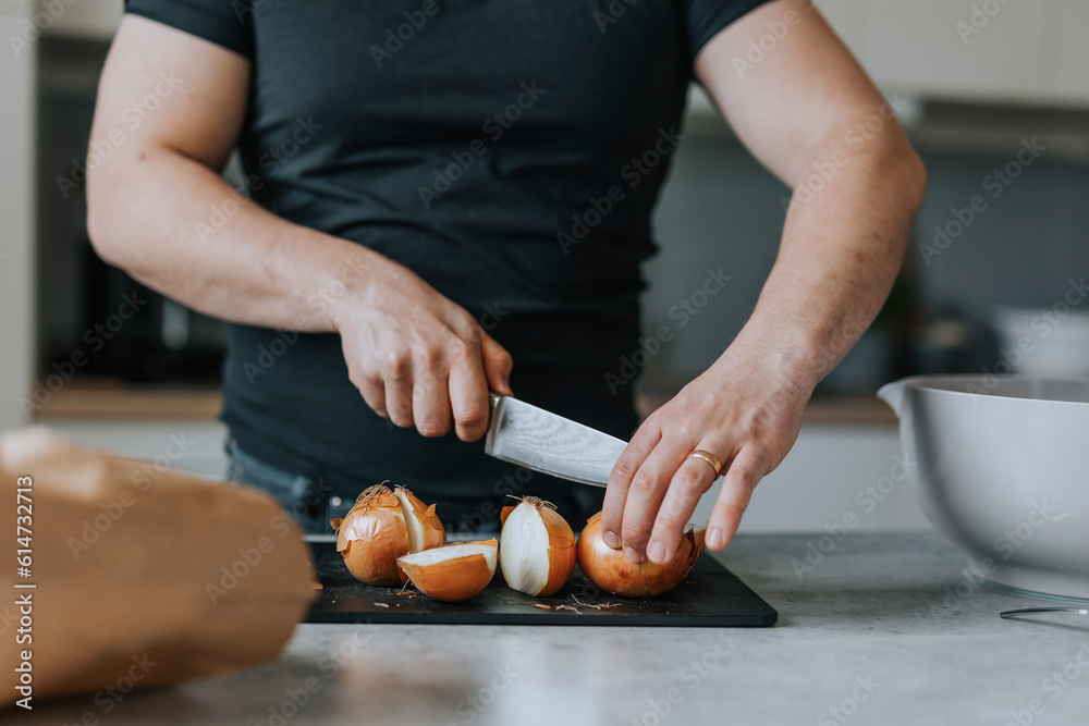 Man's hands cutting onions on cutting board in kitchen Man's hands cutting onions on cutting board in kitchen