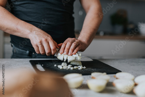 Man's hands chopping onions on cutting board in kitchen photo