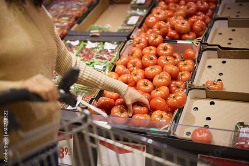 Woman's hand holding beefsteak tomato in supermarket