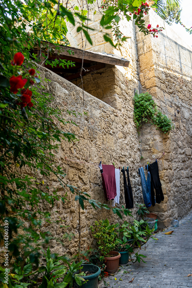 Fototapeta premium A street by traditional Kyrenia stone houses in the old town. Stone wall with clothes on a rope hanging outside in Kyrenia or Girne, Northern Cyprus.