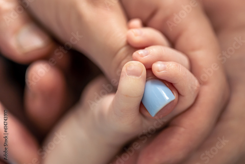 The small hand of a newborn holds the mother's finger.