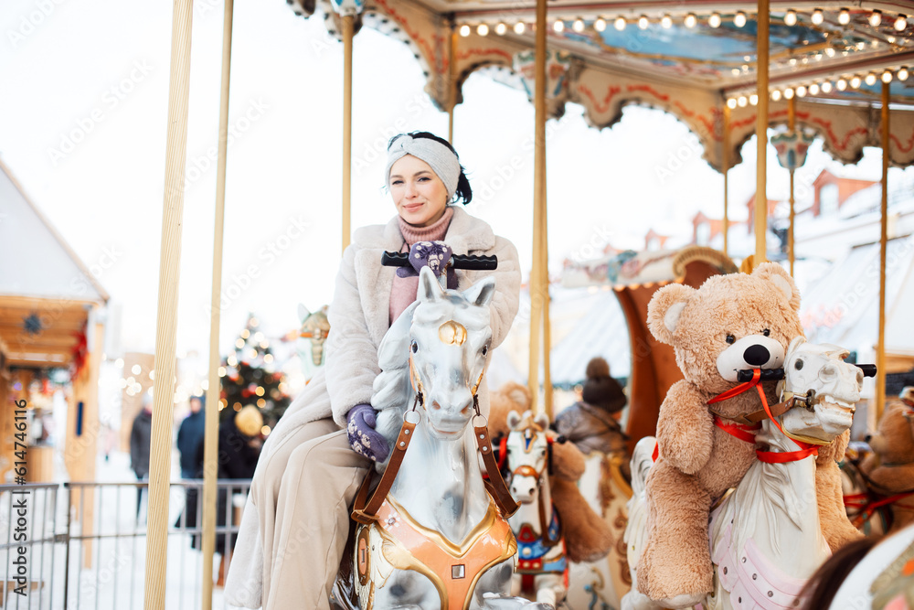 Beautiful woman on a carousel. The model is saddled on a horse and having fun during the winter holidays.