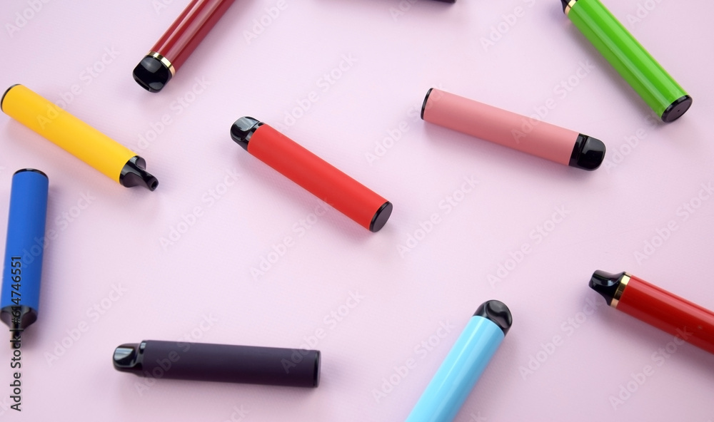 Set of multicolor disposable electronic cigarettes on a pink background.