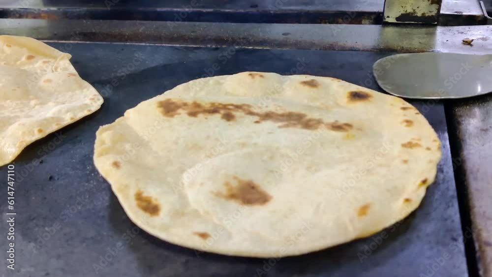 A closeup of an Indian chef skillfully preparing fresh chapatis on a