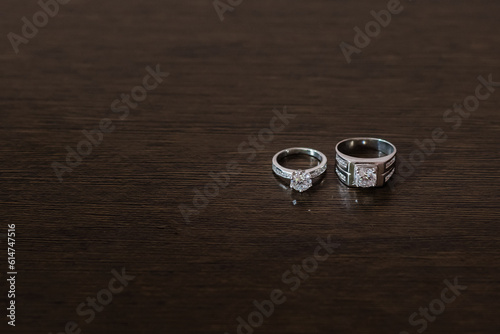 Wedding rings on a dark brown wood grain background. A couple's diamond ring against a wooden background.