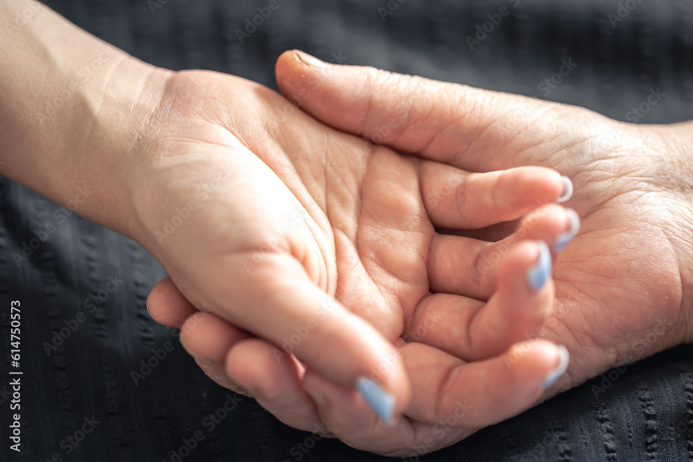 An elderly woman holds the hand of a young woman, close-up. An elderly woman holds the hand of a young woman, close-up.