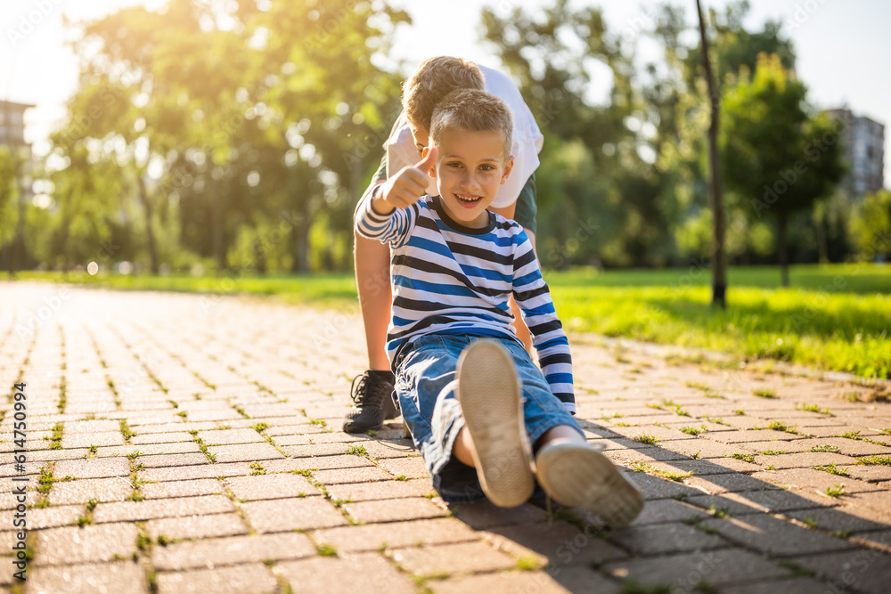 Two boys are having fun with skateboard in park. Playful children in park, happy childhood. Two boys are having fun with skateboard in park. Playful children in park, happy childhood.