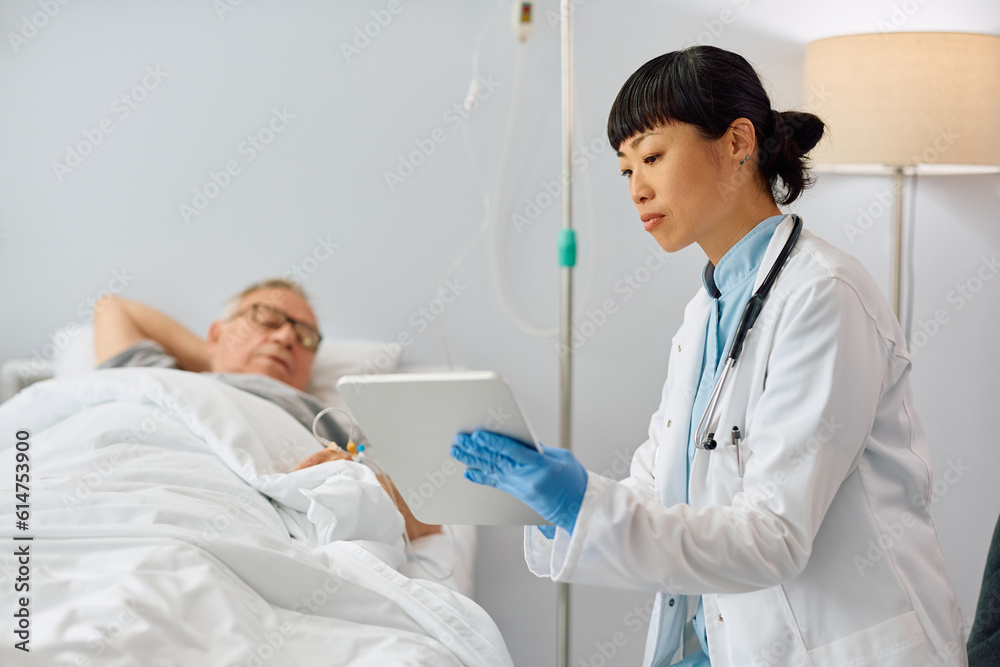 Japanese doctor and her senior patient looking at medical test results on touchpad in hospital room. Japanese doctor and her senior patient looking at medical test results on touchpad in hospital room.