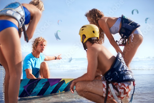 Obraz na płótnie Man teaching friends kiteboarding on sunny beach