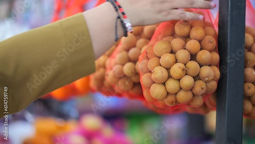 an Indonesian woman's hand choosing longan in supermarket. Advertise, Business, Food Concept - Fresh longan fruit. photo