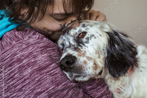 Young smiling woman hugging english setter dog in home interior close-up photo