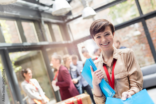 Obraz na plátne Portrait smiling young woman handing out packets at conference