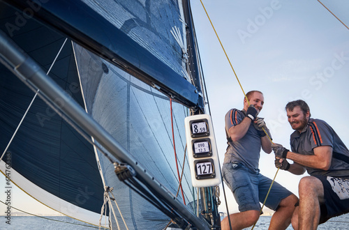Men sailing pulling rigging equipment on sailboat