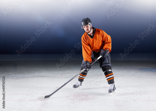 Portrait confident hockey player in orange uniform on ice