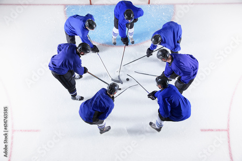 Photography Hockey players in blue uniforms huddling around puck on ice