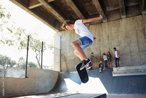 Teenage boy flipping skateboard at skate park