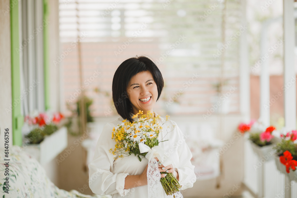 Happy female gardener with bouquets on the terrace. woman on a garden swing with a bouquet of wildflowers Happy female gardener with bouquets on the terrace. woman on a garden swing with a bouquet of wildflowers