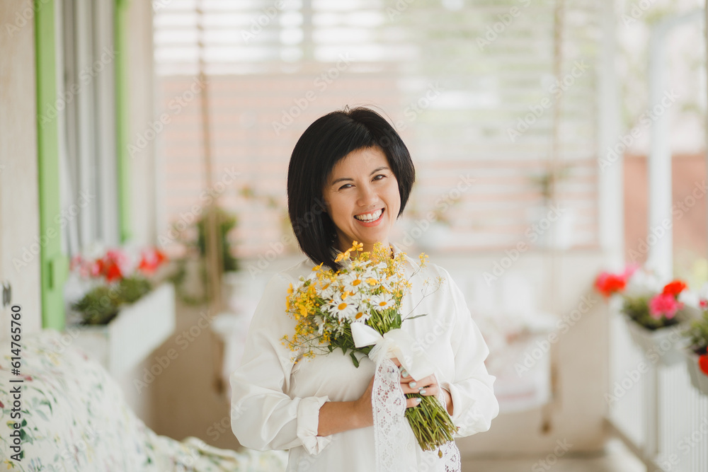 Happy female gardener with bouquets on the terrace. woman on a garden swing with a bouquet of wildflowers Happy female gardener with bouquets on the terrace. woman on a garden swing with a bouquet of wildflowers