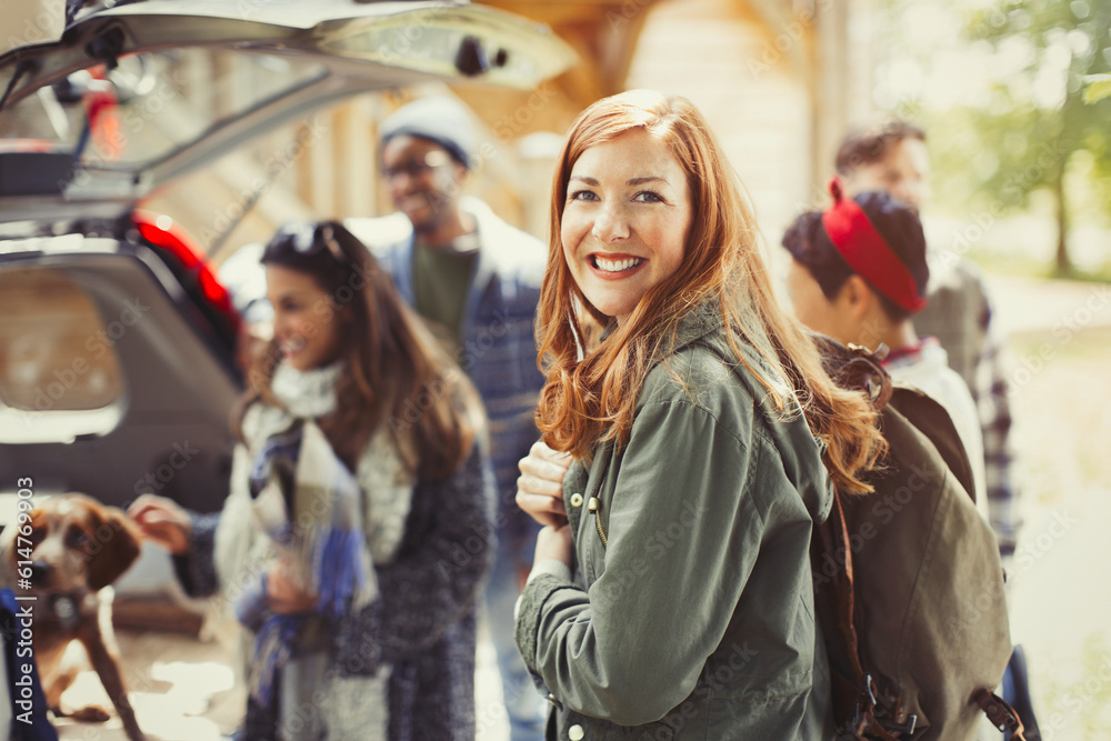 Portrait smiling hiker holding backpack with friends at back of car