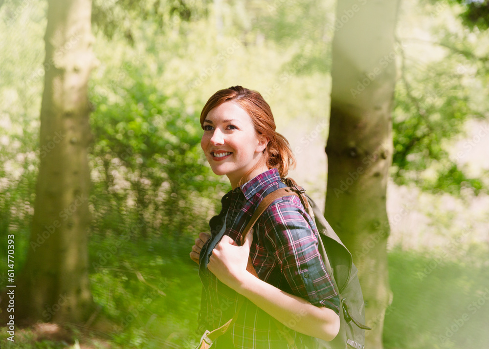 Smiling woman with backpack hiking in sunny woods Smiling woman with backpack hiking in sunny woods