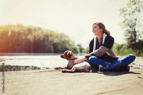 Canvas Print Smiling woman and dog relaxing on sunny lakeside dock